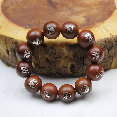 Silver-Inlaid Taoist Nine-Syllable Mantra Bracelet on a wooden surface with silver characters inlaid.